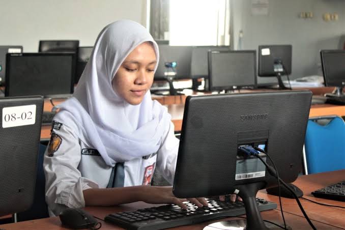Siswa berdiskusi tentang kode program di ruang praktik